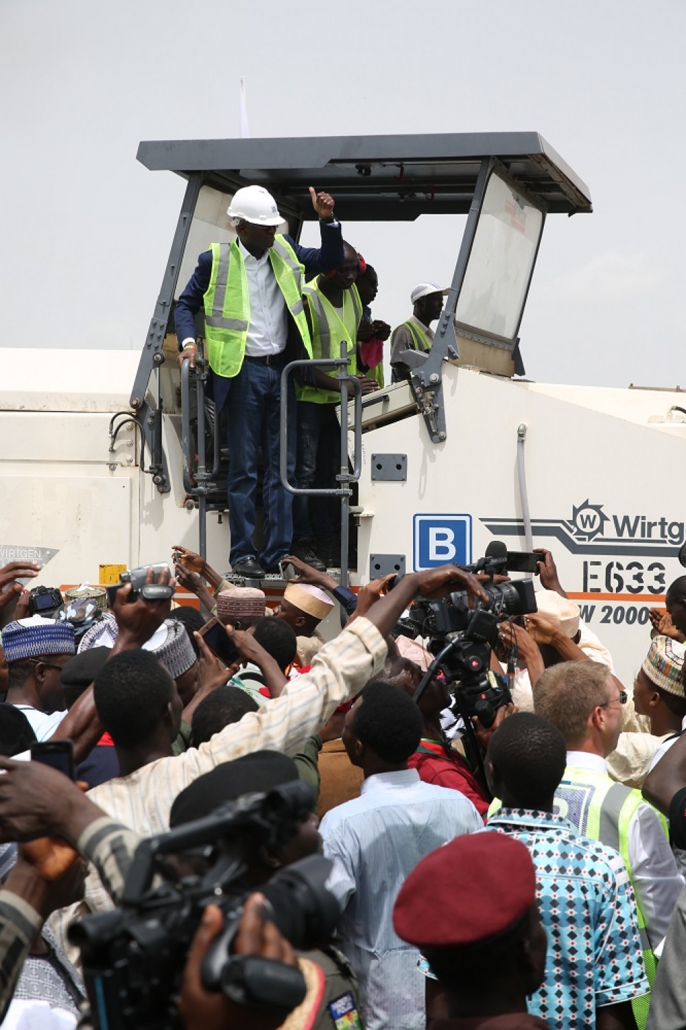 Hon Minister of Power Works  Housing Mr Babatunde FasholaSAN left acknowledges cheers from Guests and members of the beneficiary communities shortly after operating the Milling machine to formally flag off the reconstruction of the Abuja KadunaZariaKano dual carriageway in Chiromawa Toll Plaza Near Kano State on Tuesday 26th June 2018