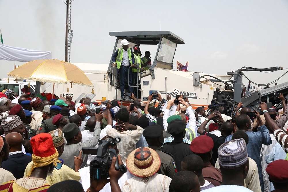 Hon Minister of Power Works  Housing Mr Babatunde FasholaSAN left surrounded by Guests and members of the beneficiary communitiesoperates the Milling machine to formally flag off  the Reconstruction of the Abuja KadunaZariaKano Dual Carriageway in Chiromawa Toll Plaza Near Kano State on Tuesday 26th June 2018