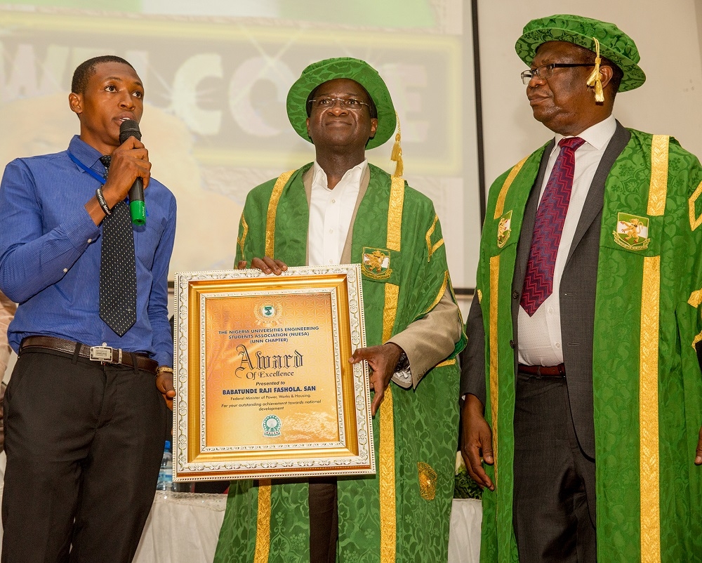 Hon Minister of Power Works  Housing and Guest Lecturer Mr Babatunde FasholaSANmiddleVice  Chancellor University of NigeriaNsukka ProfBenjamin Chukwuma Ozumbaright PresidentFaculty of Civil Engineering Students AssociationEze Kingsley Emekaleftpresenting a souvenir to the Hon Minister shortly after delivering theSpecial Herbert Macaulay Memorial Lectureorganized by the University of Nigeria Nsukka  at the Princess Alexandra AuditoriumPAA Nsukka Enugu State on Monday 2nd July 2018