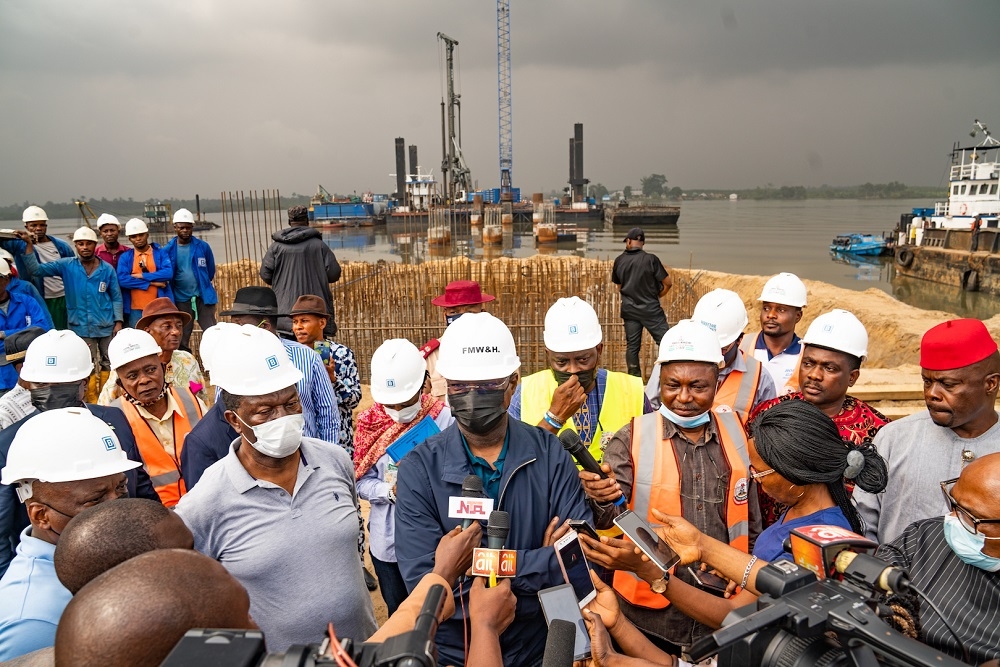 Hon. Minister of Works and Housing, Mr. Babatunde Fashola, SAN (2nd left), flanked by Director, Bridges and Design in the Ministry, Engr. Emmanuel Adeoye (left), the Project Engineering Representative, Engr. Eseme Udoh (3rd right)  and two Members of the Project&#039;s Peace Committee, HRH Mene Stephen Kpea of Mogho, Gokana LGA , Rivers State (right) and Mene Gbaragbe (2nd right) while speaking with journalists during the Inspection of the Bodo -Bonny Road with Bridges Across the Opobo Channel in Rivers State on Tuesday, 10th August 2021. Behind the Hon. Minister is the ongoing piling works on water at the Opobo Channel main Bridge at Ch.17+500.